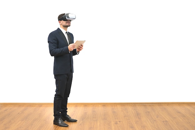 El hombre con gafas de realidad virtual sosteniendo una tableta sobre el fondo blanco.