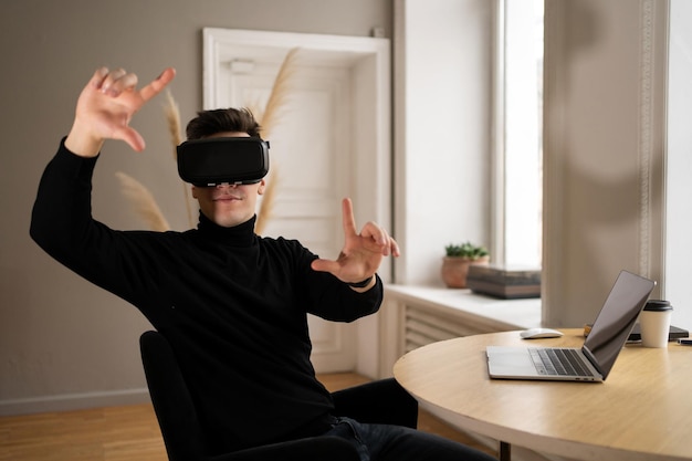 Un hombre con gafas de realidad virtual usa una computadora portátil en el informe de la empresa de oficina