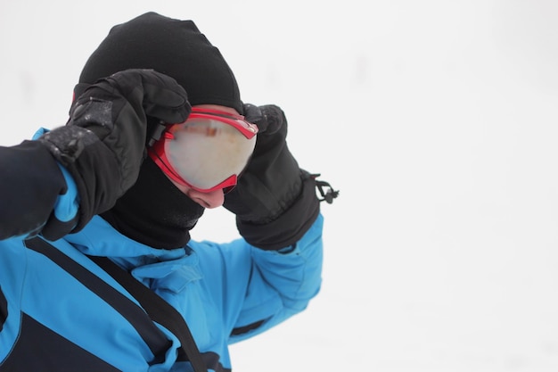Foto hombre con gafas de snowboard sobre el fondo de nieve