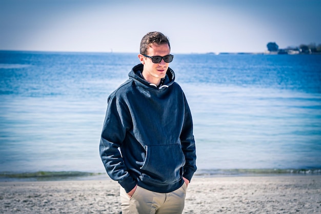 Foto hombre con gafas de sol caminando por la playa