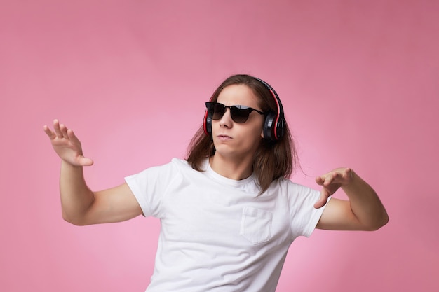 Hombre con gafas de sol escucha música con auriculares y bailes