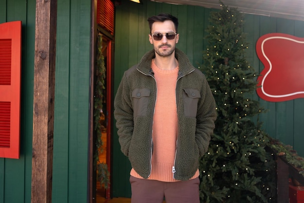 Hombre con gafas de sol de pie cerca del árbol de Navidad