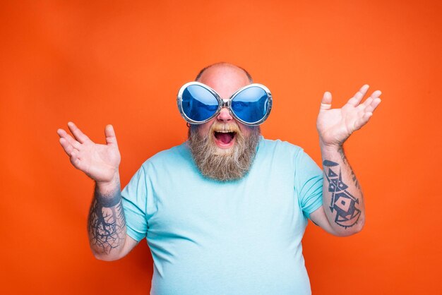 Foto hombre con gafas de sol de pie contra un fondo naranja