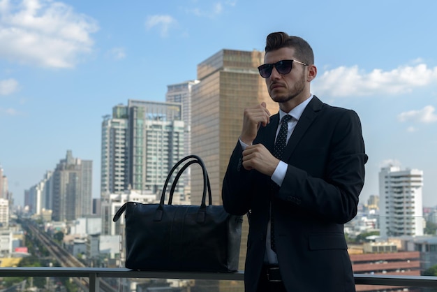 Foto hombre con gafas de sol de pie contra el paisaje urbano