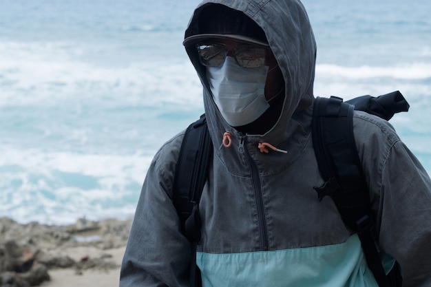 Un hombre con gafas de sol que llevaba una sudadera con capucha con una máscara médica en su rostro.