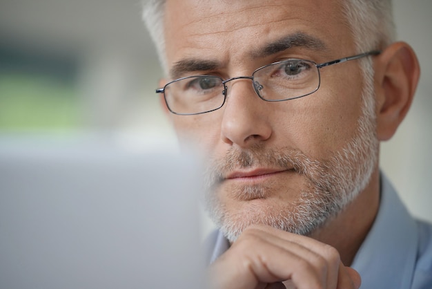 Foto hombre con gafas trabajando en una computadora