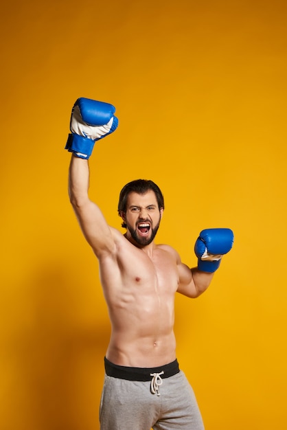 El hombre ganador en guantes de boxeo disfruta de la victoria.