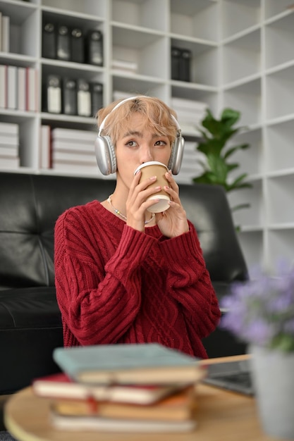 Un hombre gay disfruta de su café mientras escucha música en la sala de estar.