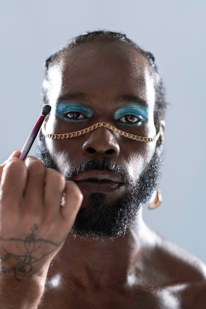 Hombre gay negro confiado con maquillaje brillante y accesorios