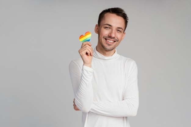 Hombre gay sonriente con corazón de arco iris