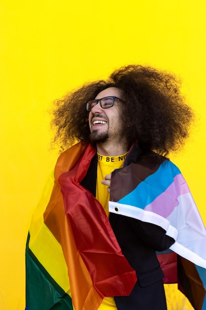 Hombre gay sonriente feliz envolviendo con una bandera lgbt del arco iris