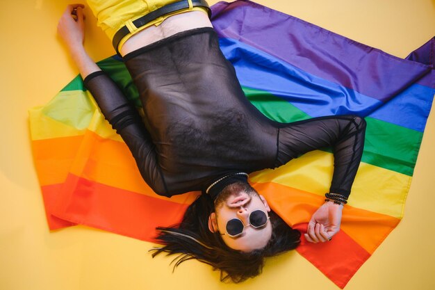 Hombre gay sostenga la bandera de rayas del arco iris aislada en el retrato de estudio de fondo de color Gente estilo de vida moda concepto lgbtq