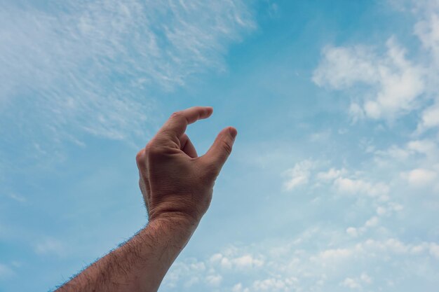 Foto hombre gestando con la mano en el cielo azul