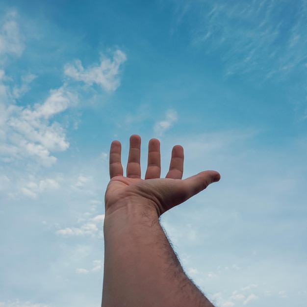 hombre gestando con la mano en el cielo azul