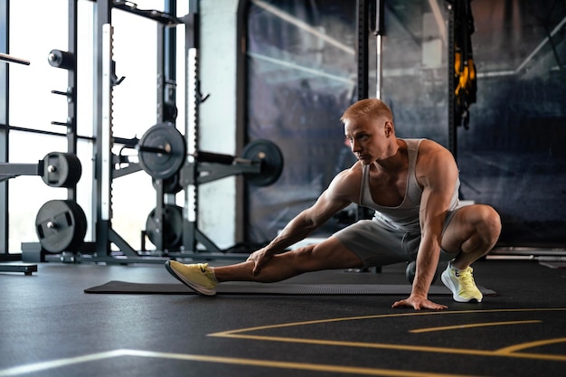 Hombre en el gimnasio haciendo ejercicios de estiramiento en el suelo