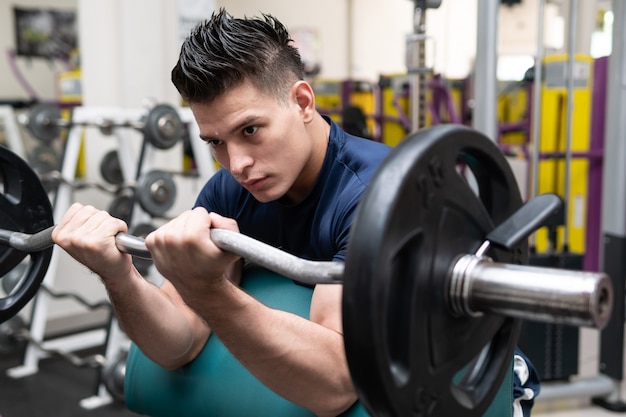 Foto hombre en el gimnasio levantando pesas con entrenamiento fuerte