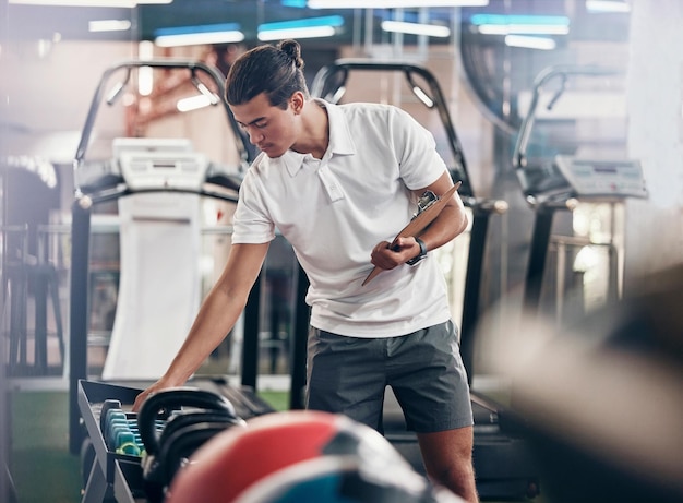 Hombre de gimnasio y portapapeles de equipo con un gerente masculino revisando pesas en un club de salud para hacer ejercicio Ejercicio y deportes con un joven escribiendo notas o una lista para un estilo de vida saludable