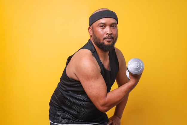 Hombre gordo barbudo divertido y emocionado en ropa deportiva divirtiéndose mientras hace ejercicios deportivos con pesas