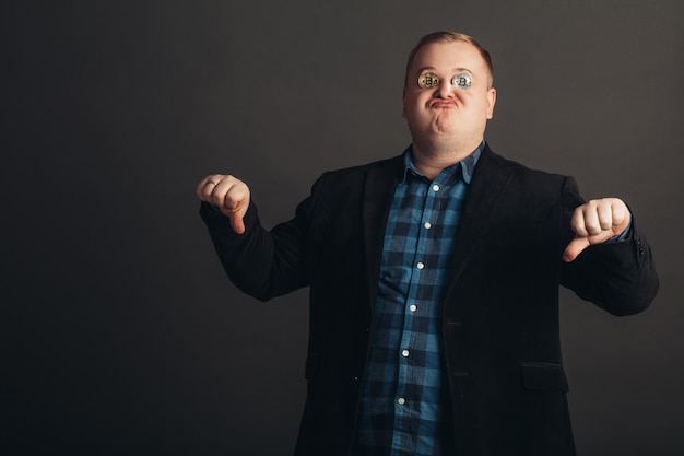 Hombre gordo celebrando una cara loca amante loco de bitcoin con una moneda de oro en los ojos