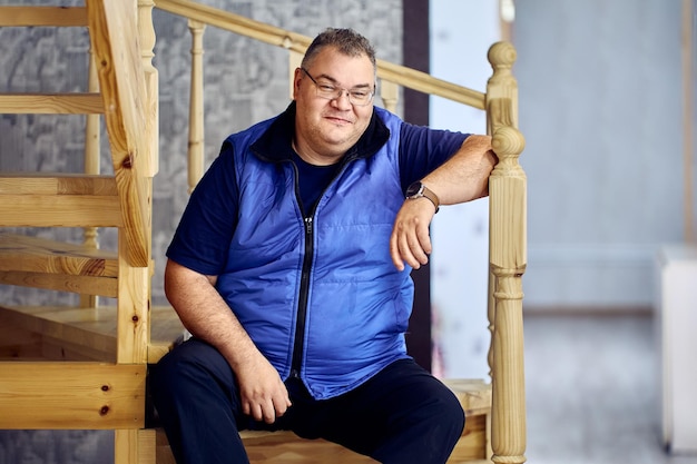 Un hombre gordo de cuarenta años, sonriente y bondadoso, se sienta en las escaleras que conducen al segundo piso de una casa en los suburbios.