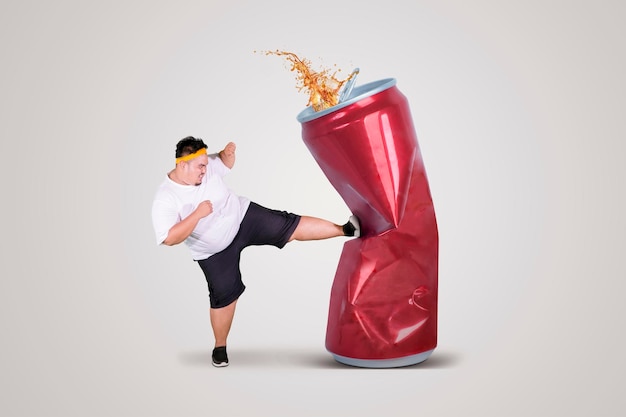 Hombre gordo enojado pateando una lata de refresco