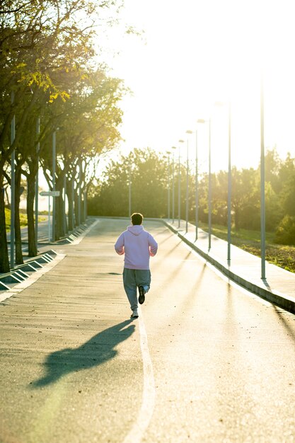 Foto hombre gordo de espaldas corriendo cuesta arriba por el medio de la calle