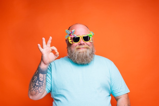 Hombre gordo feliz con tatuajes de barba y gafas de sol está listo para el verano