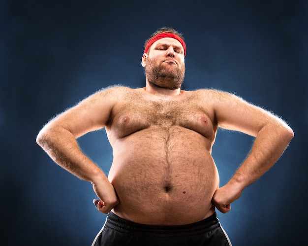 Hombre gordo imitando la estructura muscular. Vista de ángulo bajo