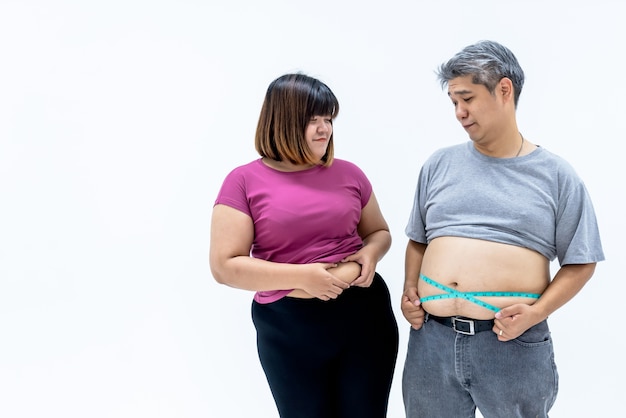 Hombre gordo y mujer mirando la grasa del vientre del otro