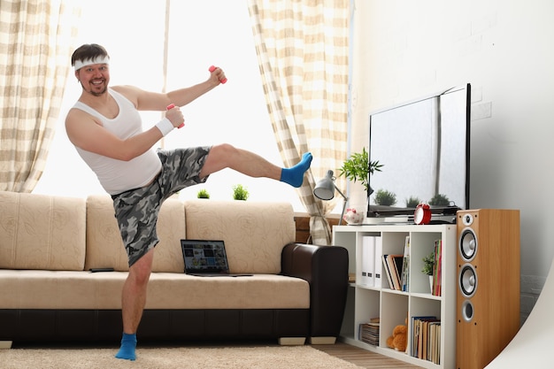 Hombre gordo en ropa deportiva y pesas hace ejercicio físico