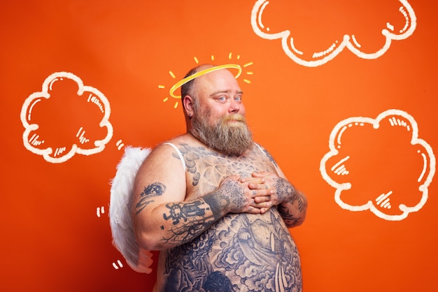 Hombre gordo con tatuajes de barba y alas actúa como un ángel