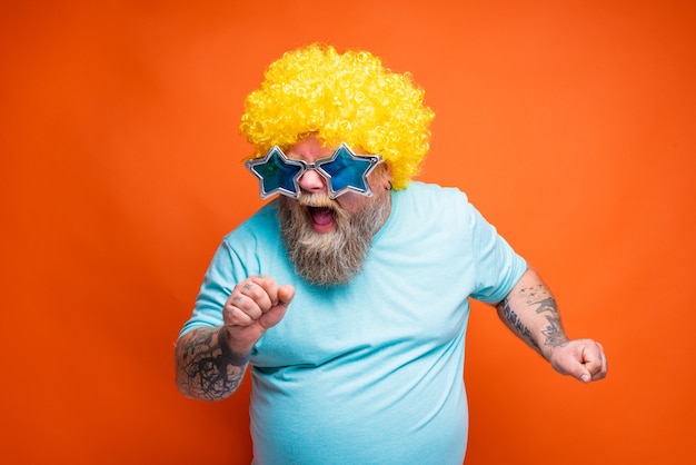 Foto hombre gordo con tatuajes de barba y gafas de sol canta una canción