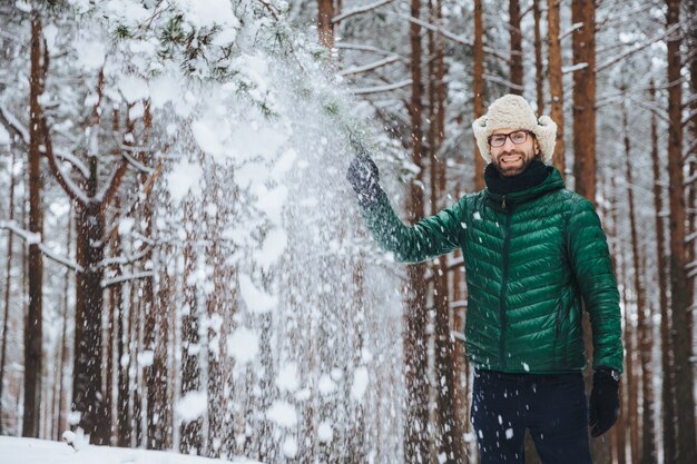 hombre con gorra de piel con orejeras jugando con nieve