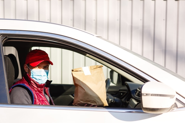 Hombre de gorra roja dando orden de comida rápida. El mensajero tiene un paquete de papel con comida. Entrega de productos desde tienda o restaurante a domicilio.