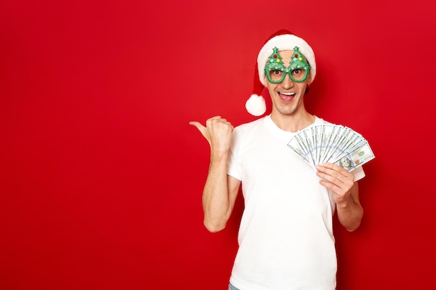 Hombre con gorro de Papá Noel con fajo de puntos de dinero dedo libre concepto vacío inversión de reembolso de crédito