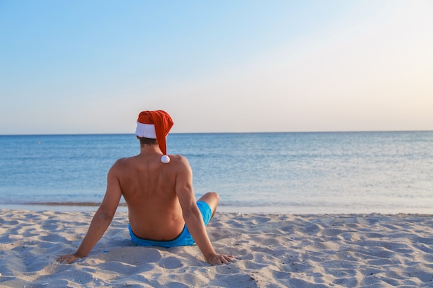 Hombre con gorro de Papá Noel en la playa