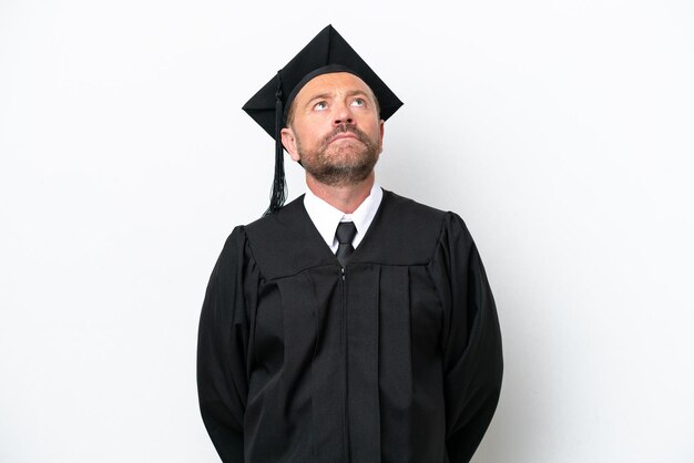 Hombre graduado universitario de mediana edad aislado de fondo blanco y mirando hacia arriba