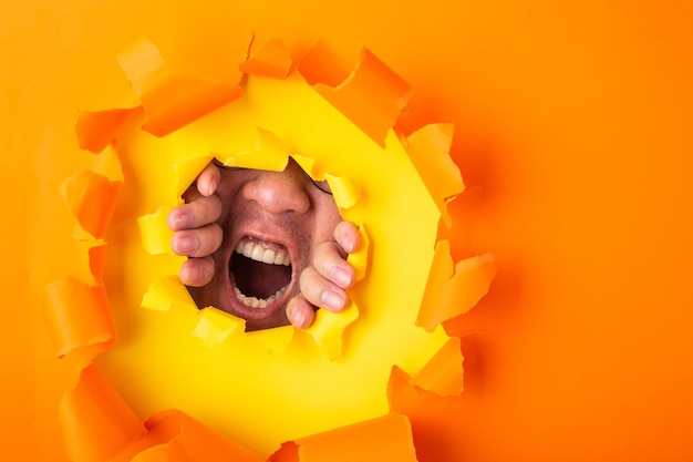 Foto hombre gritando desde detrás de un agujero de papel