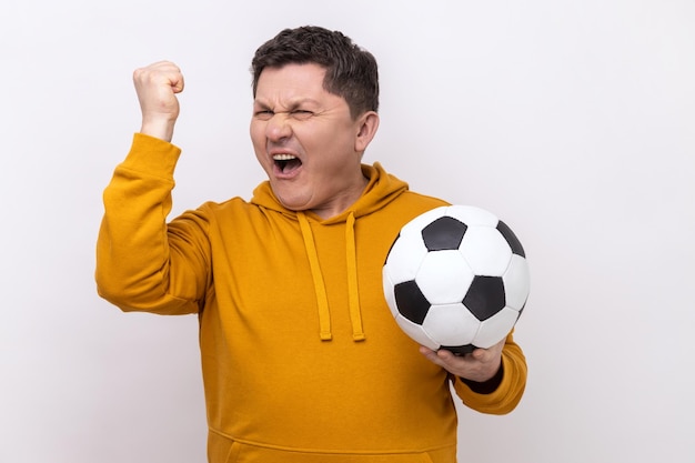 Hombre gritando sosteniendo un balón de fútbol celebrando la victoria del equipo de fútbol favorito en el campeonato