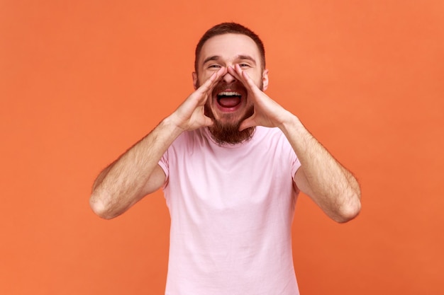 Hombre gritando en voz alta abriendo la boca con las manos en la cara gritando anunciando su opinión