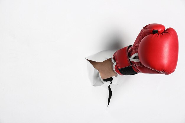 Hombre en guante de boxeo rompiendo papel blanco