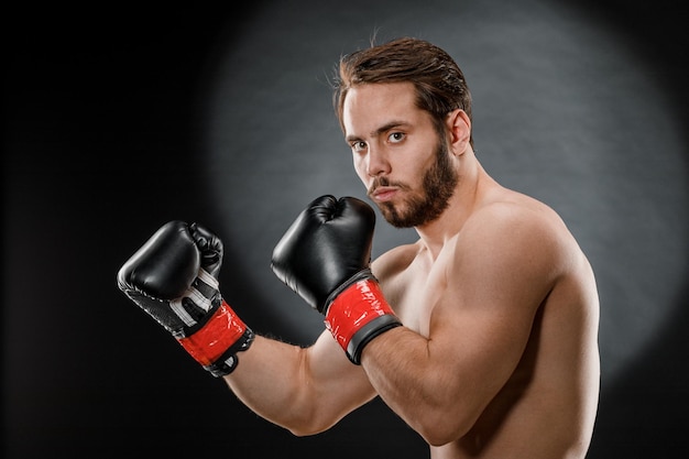 Un hombre con guantes de boxeo. un hombre de boxeo sobre un fondo negro. el  concepto de estilo de vida saludable.