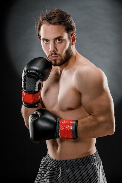 Un hombre con guantes de boxeo. Un hombre de boxeo sobre un fondo negro. El concepto de estilo de vida saludable.