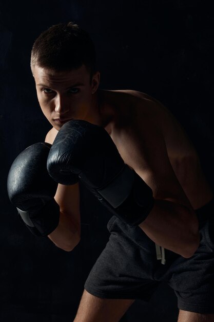 Hombre en guantes de boxeo sobre fondo negro entrenamiento culturista fitness