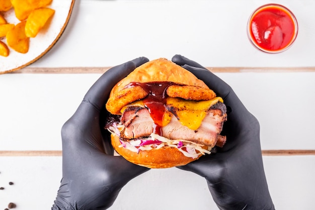 El hombre con guantes negros sostiene una hamburguesa. El hombre come hamburguesa. Vista superior