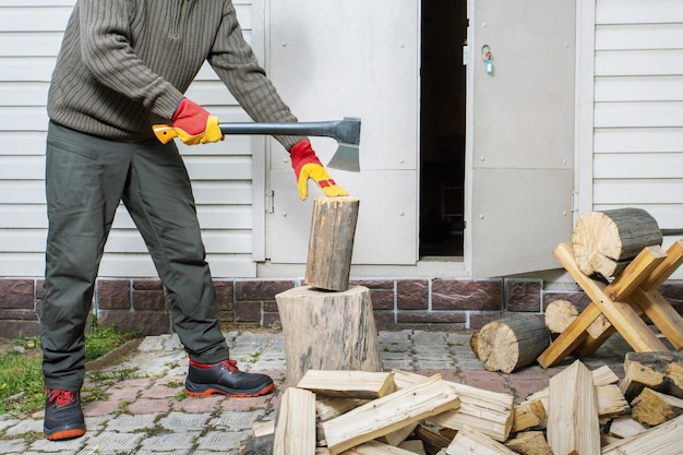 Hombre con guantes protectores cortando leña