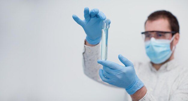 Hombre en guantes con tubo de ensayo