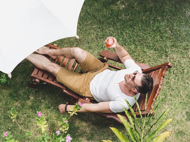 Hombre guapo acostado en una silla de sol