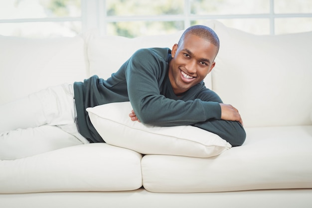 Hombre guapo acostado en el sofá y sonriendo a la cámara