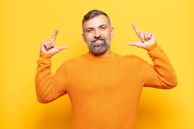 Hombre guapo adulto enmarcando o delineando su propia sonrisa con ambas manos, luciendo positivo y feliz, concepto de bienestar